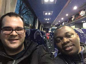 Brian and John sit in the interior of a bus