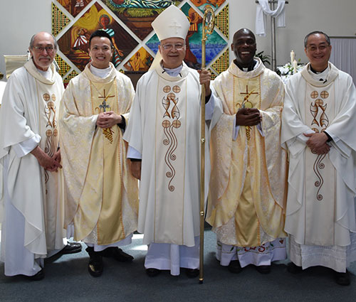 Two newly ordained priests with bishop