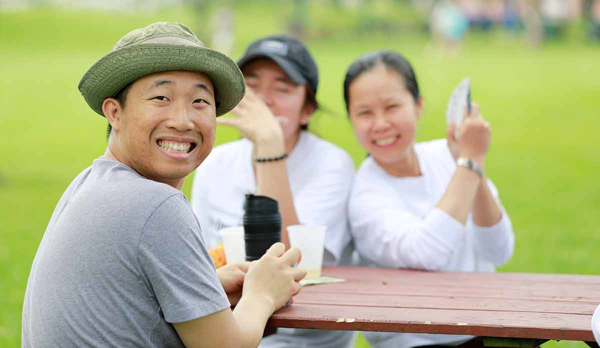 Asian man looking over shoulder while laughing with two women